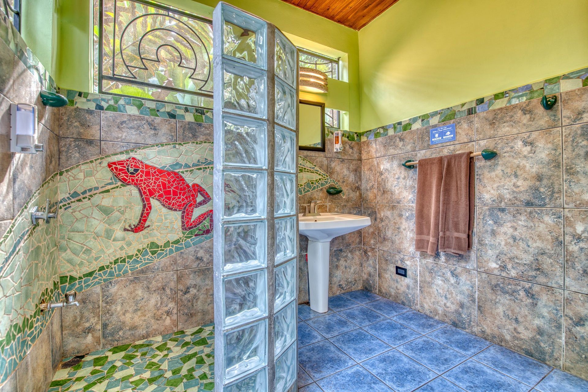 A bathroom with a frog on the wall and a frog in the shower.