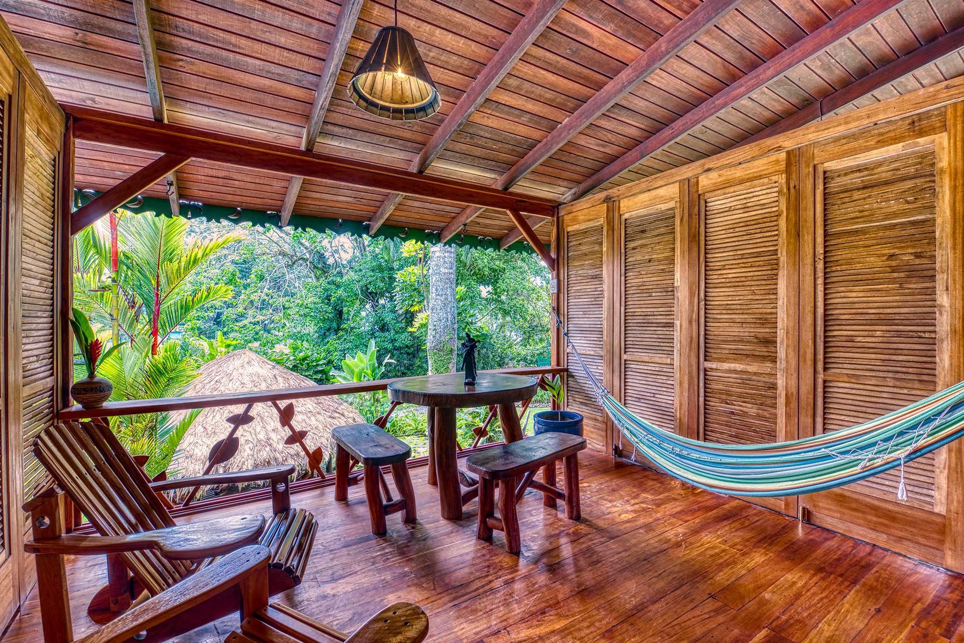 A wooden porch with a table and chairs and a hammock.