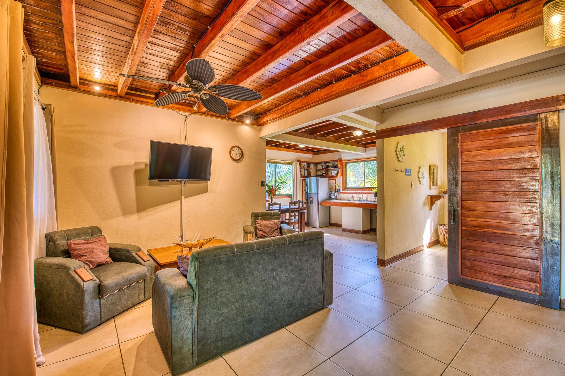A living room with a couch , chair , television and ceiling fan.