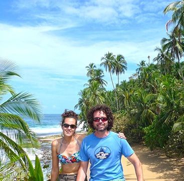 A man and a woman are posing for a picture on a beach