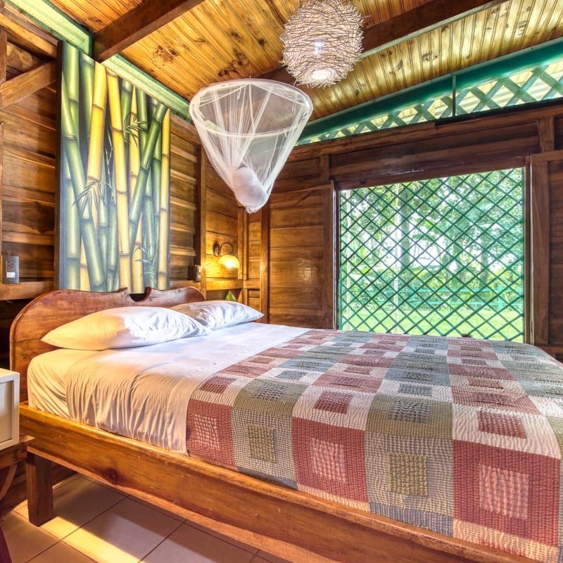A bedroom with a bed and a window with a mosquito net hanging from the ceiling