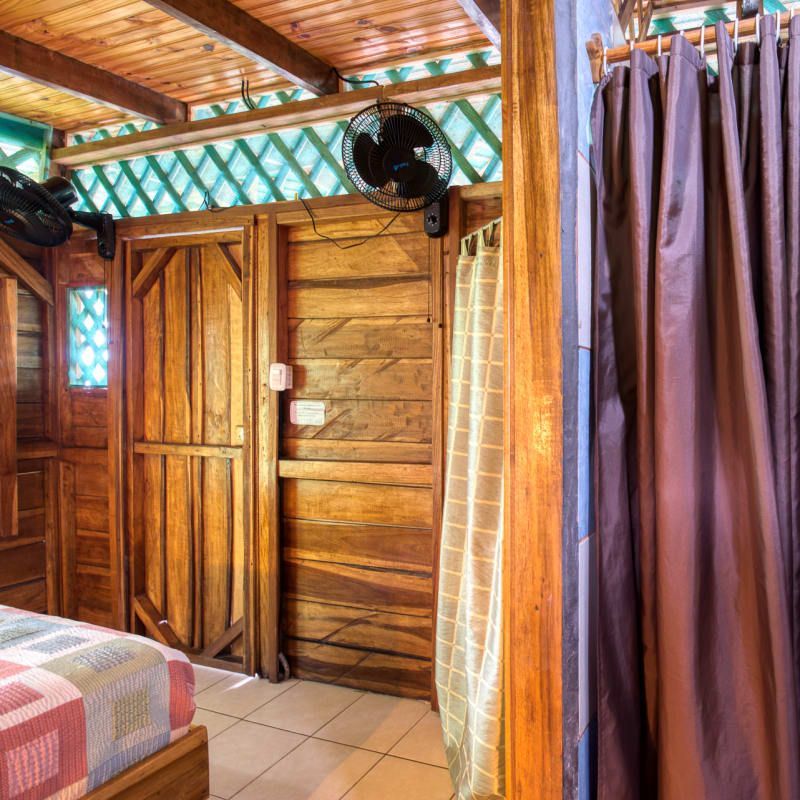 A bedroom with a bed a fan and a shower curtain