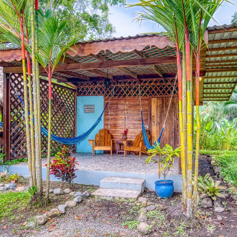A wooden house with a hammock and chairs in front of it.