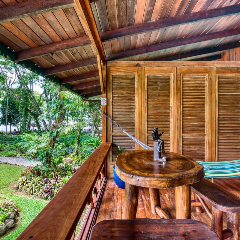A wooden balcony with a table and a hammock
