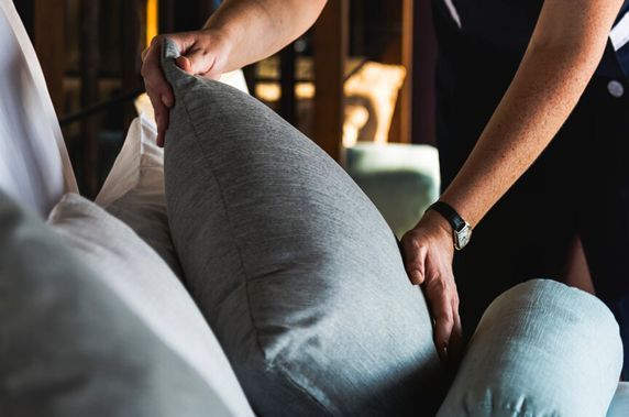 A person is putting a pillow on a couch.