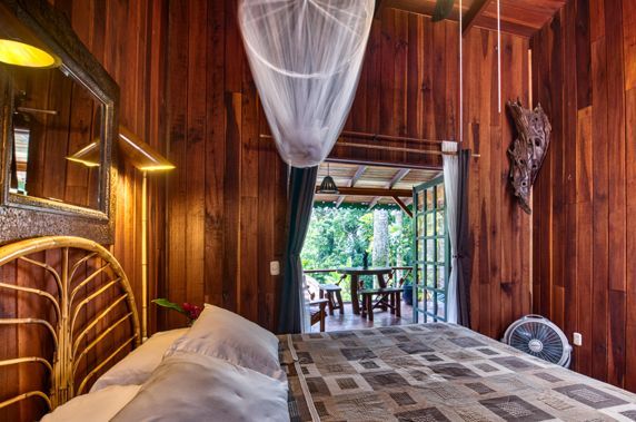 A bedroom with a bed and a mosquito net hanging from the ceiling.