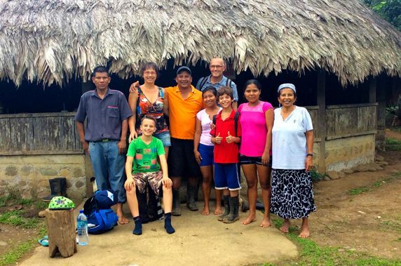 A group of people are posing for a picture in front of a thatched hut.