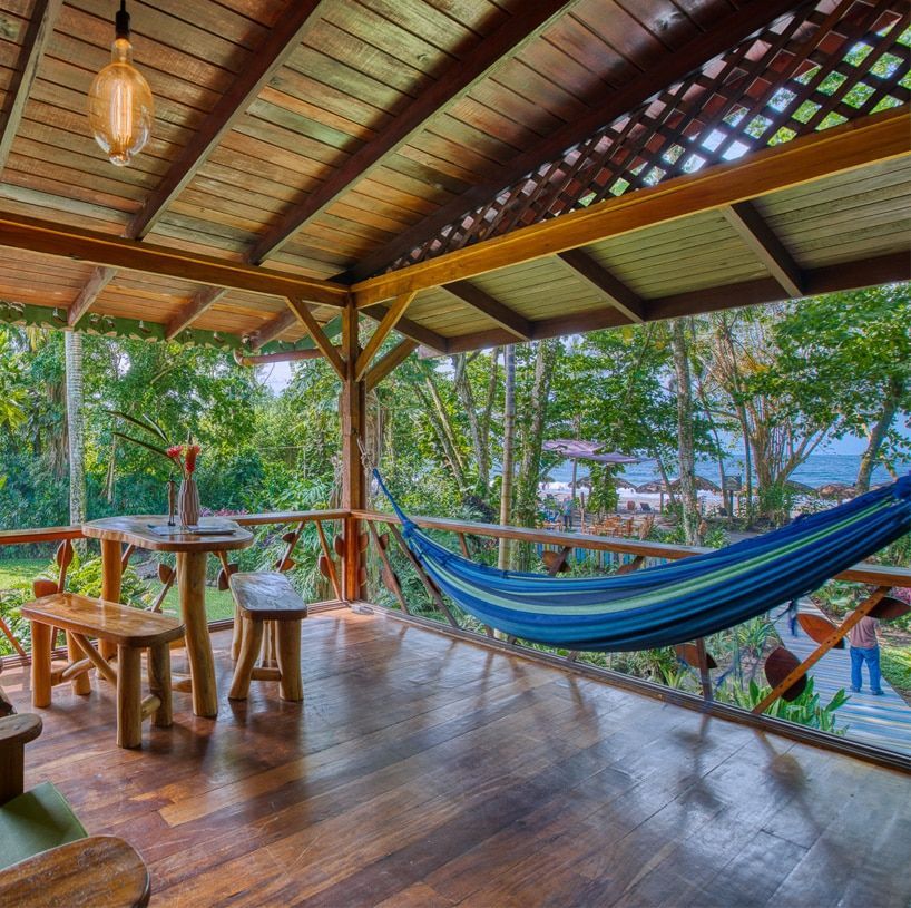A wooden porch with a hammock and a table