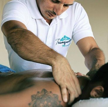 A man in a tranquil massage shirt is massaging a man 's back