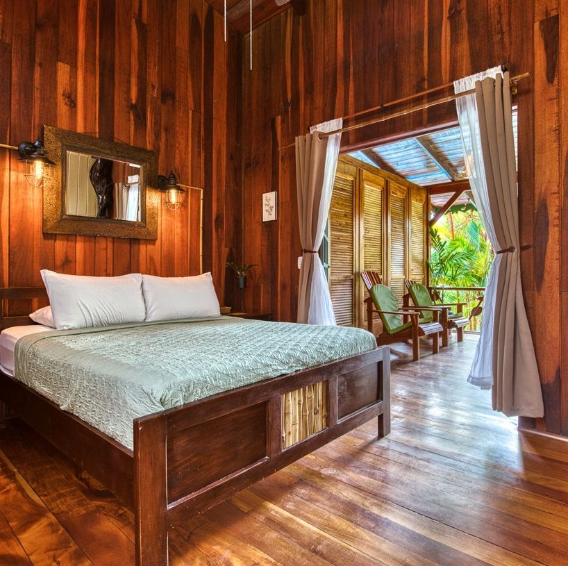 A bedroom with a bed , chairs and a mirror.