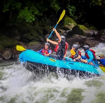 A group of people are rafting down a river in a blue raft.