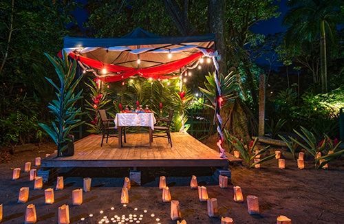 A table and chairs under a canopy with candles on the ground.