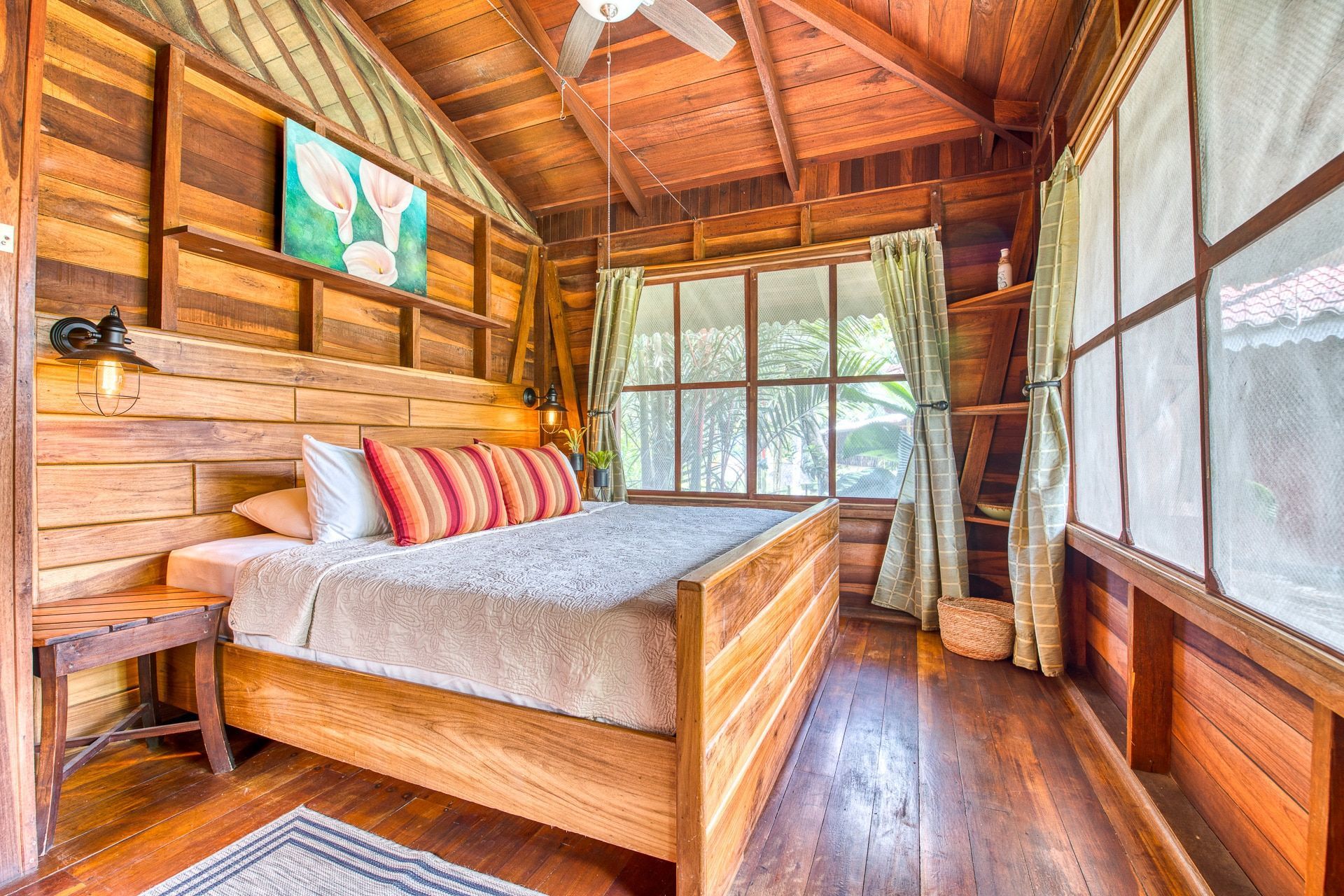 A wooden bedroom with a king size bed and a ceiling fan.