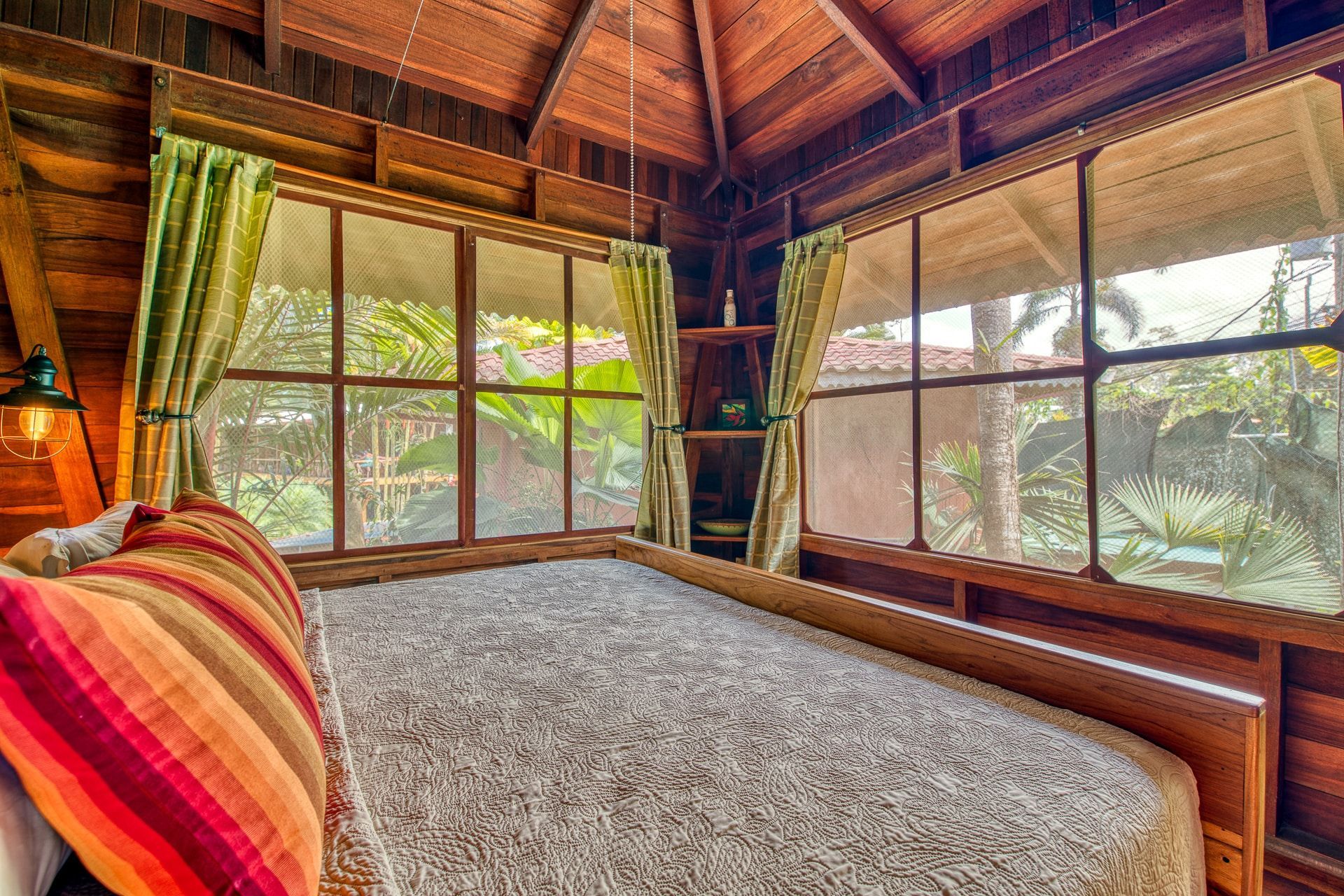 There is a bed in the middle of the room with a lot of windows.