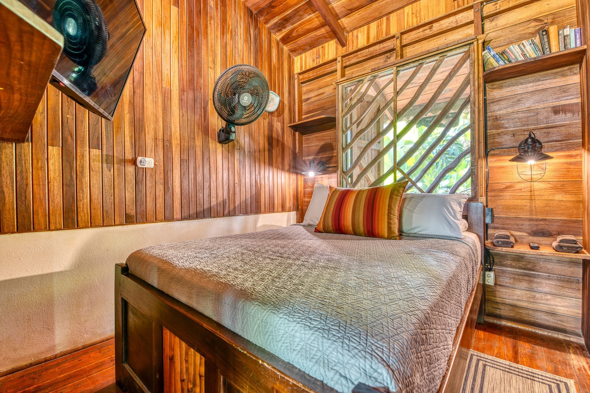 A bedroom with a bed , nightstands , and a fan.