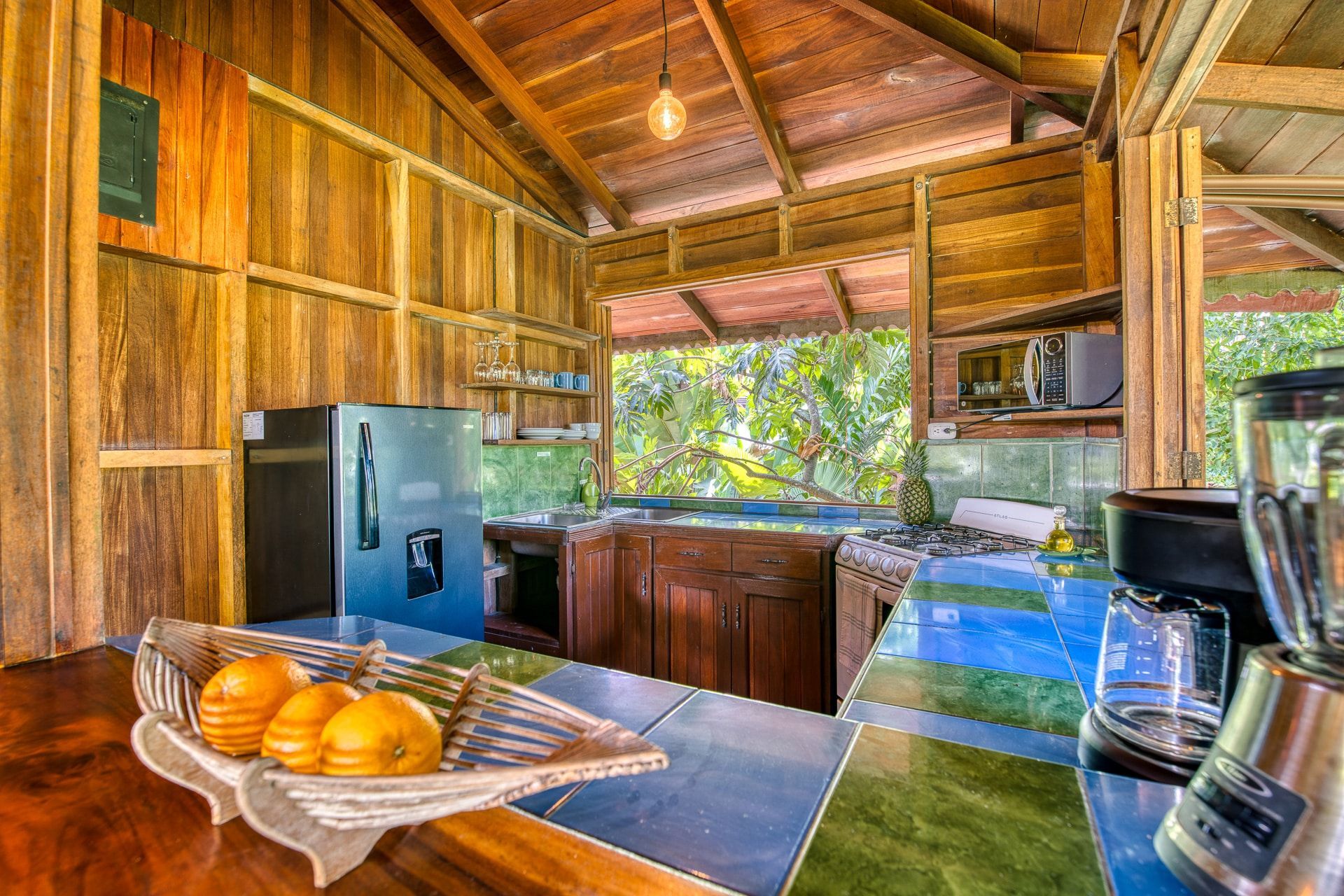 A kitchen with a blender and a bowl of fruit on the counter.