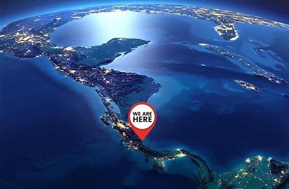 An aerial view of the earth with a red pin that says we are here