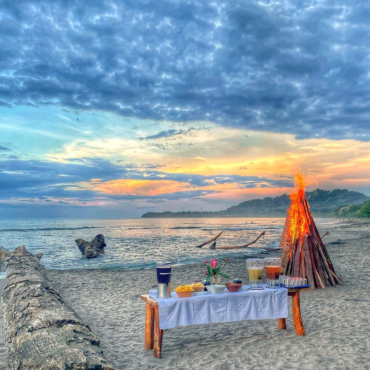 A table on the beach with a fire in the background