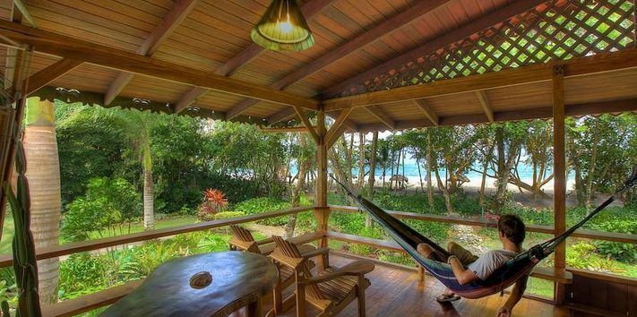 A man is sitting in a hammock on a porch.