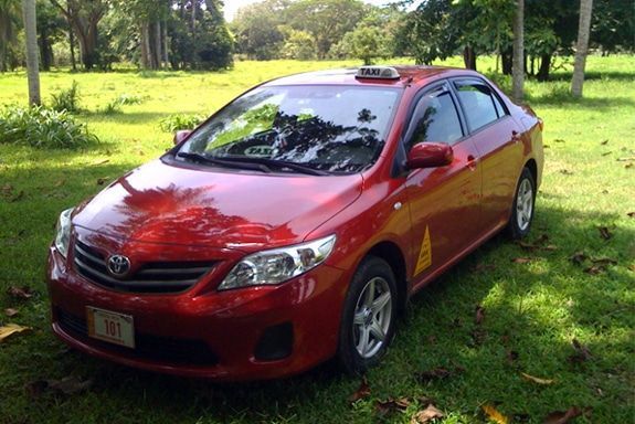 A red car is parked in a grassy field.