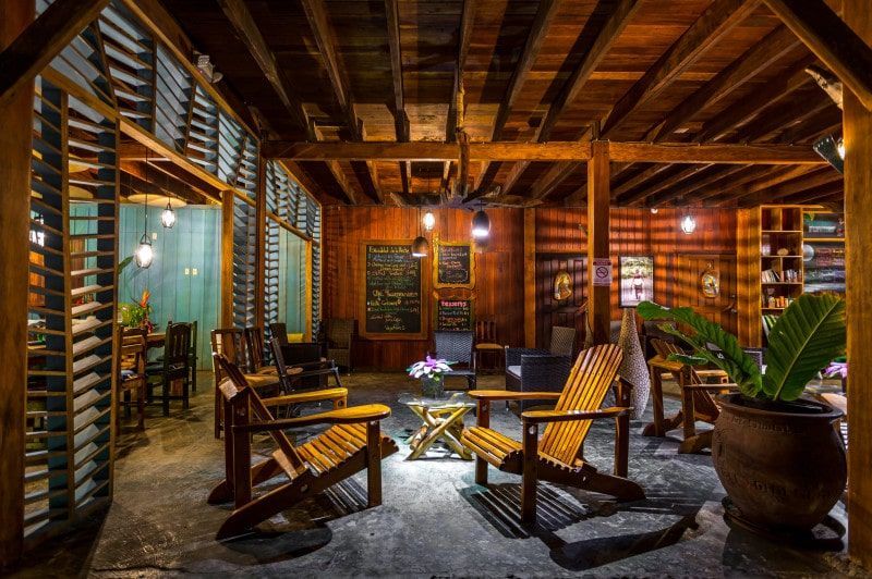 A living room with wooden chairs , a table and a potted plant.