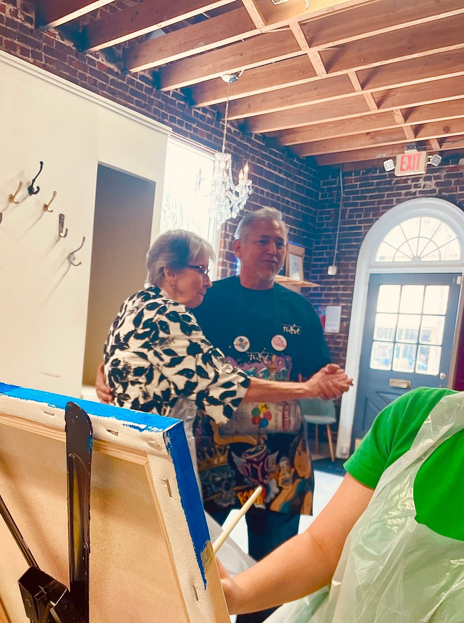 A man and a woman are dancing in a room with a brick wall.