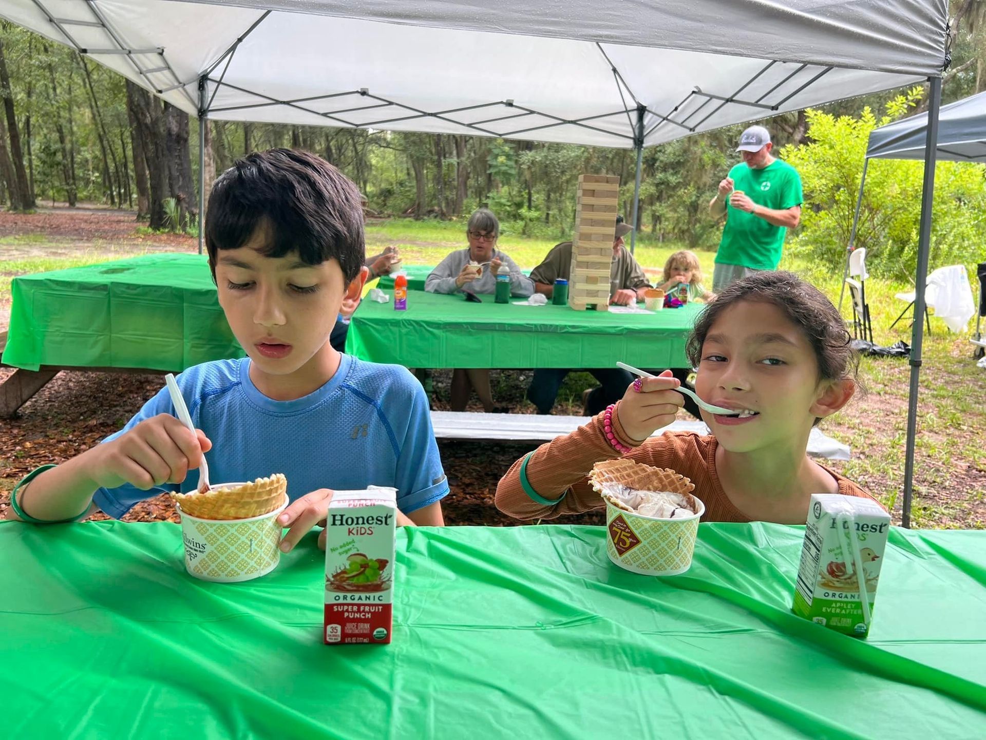 A boy and a girl are sitting at a table eating food.