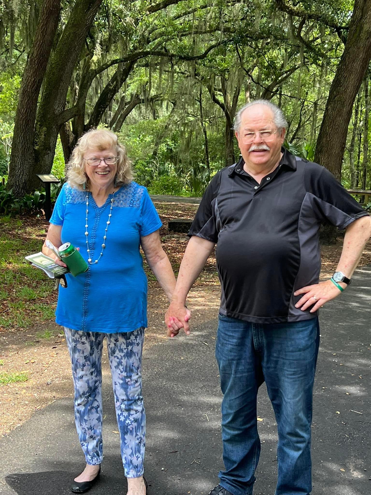 A man and a woman are holding hands in a park.