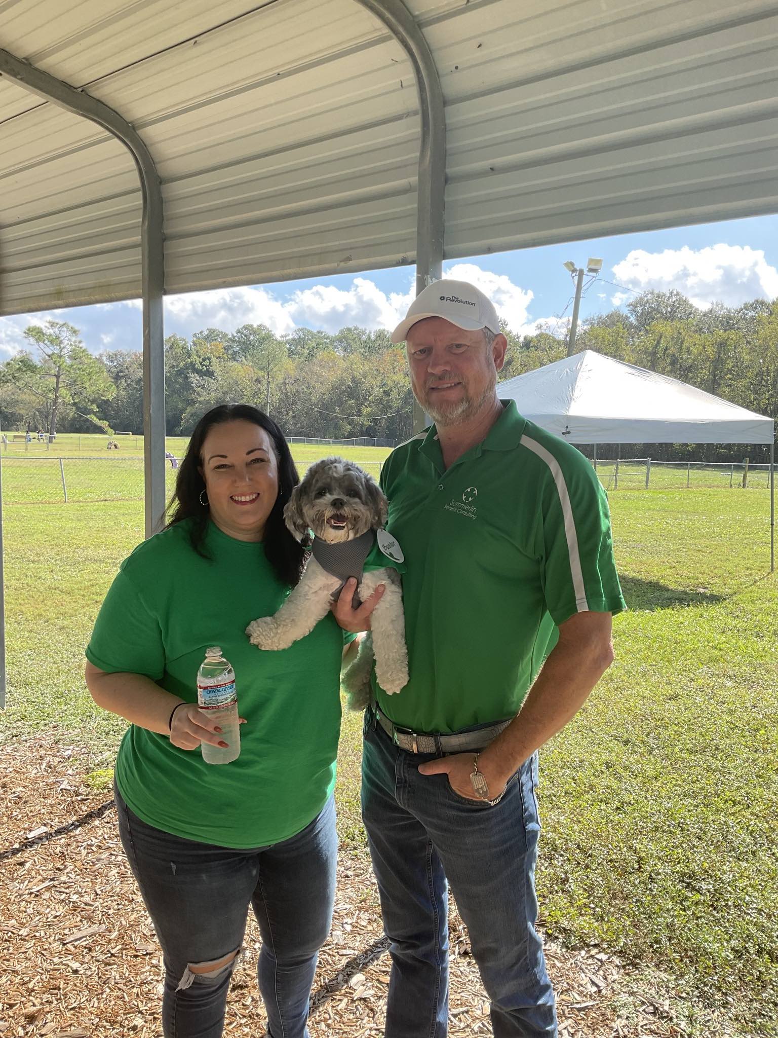 A man and a woman are standing next to each other holding a small dog.