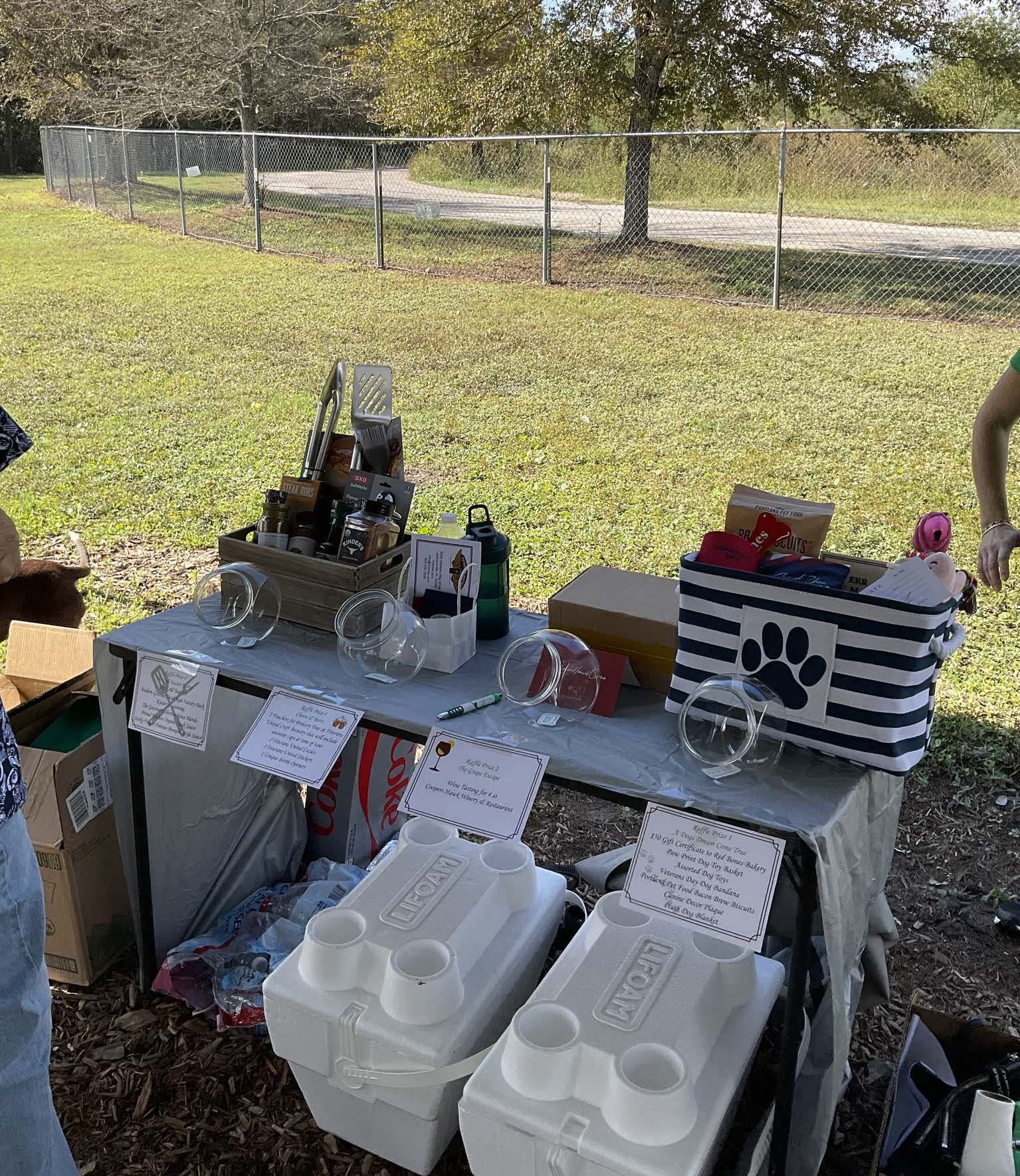 A table with coolers and a basket with a paw print on it.