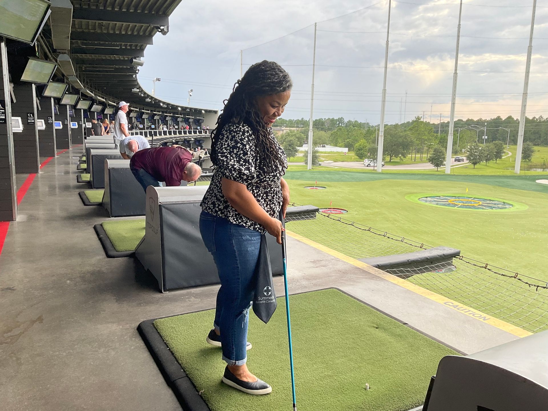 A woman is standing on a golf course holding a golf club.
