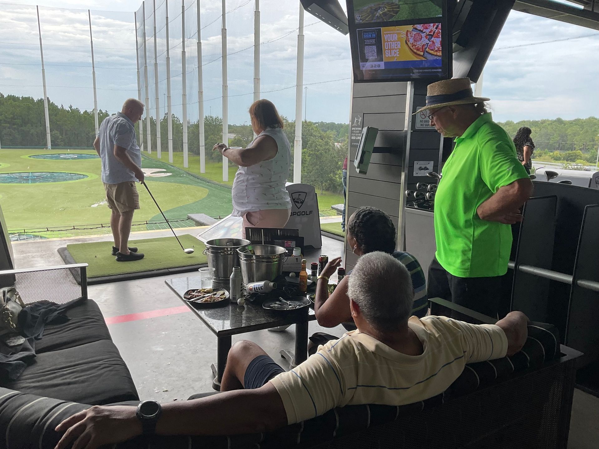 A group of people are sitting in a living room looking out a window at a golf course.