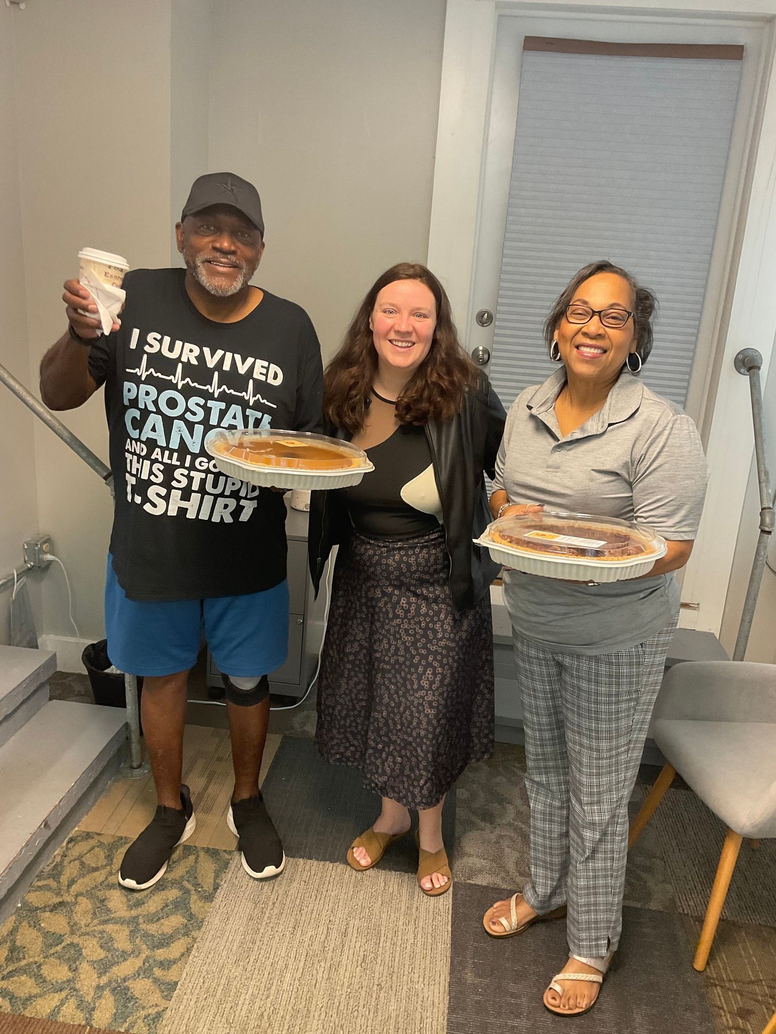 A man and two women are standing next to each other holding plates of food.
