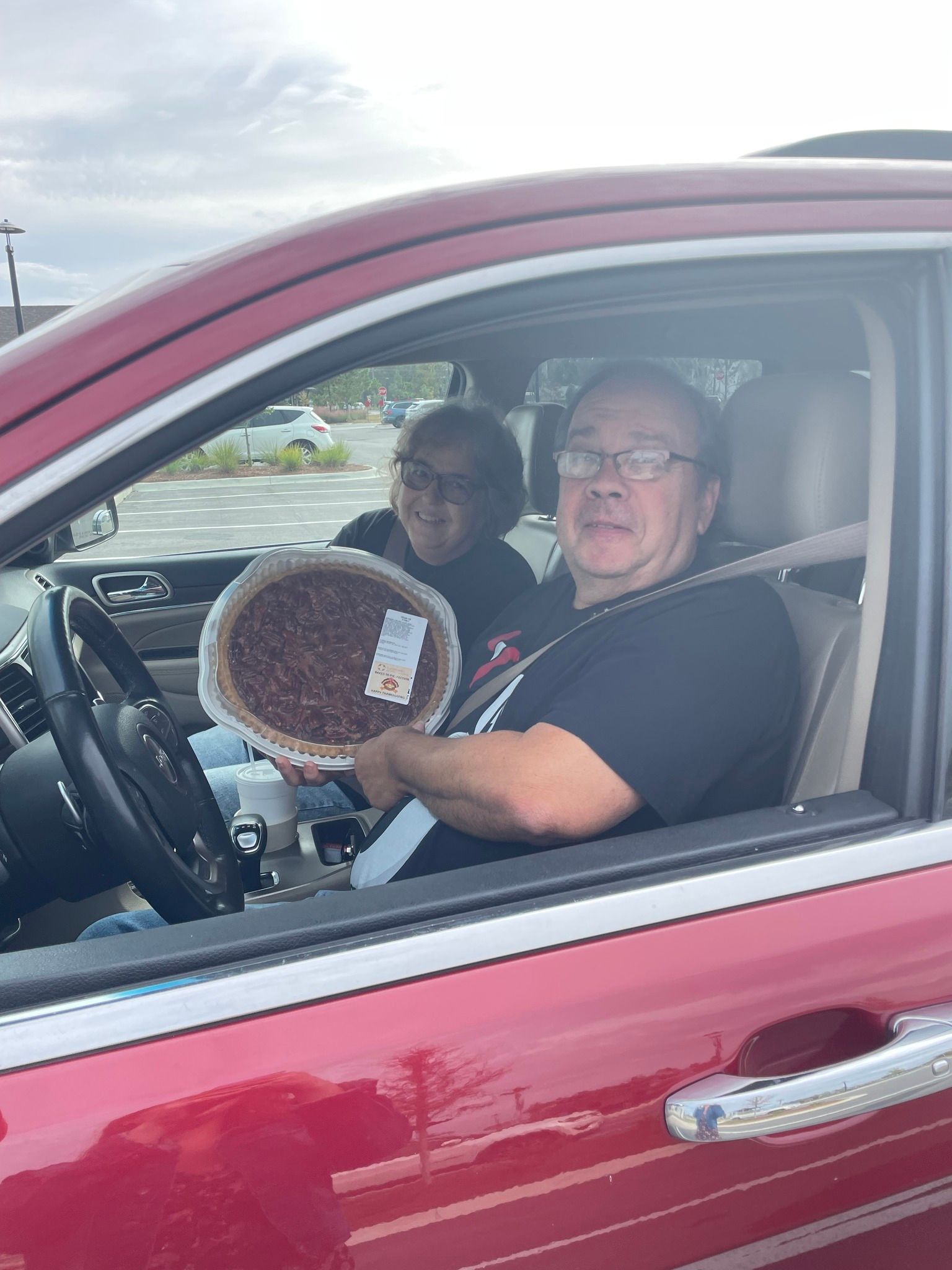A man is sitting in a car holding a pie.