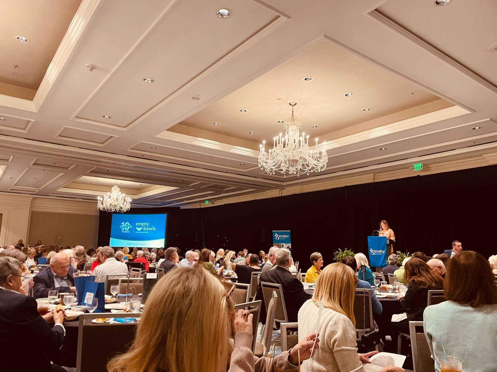A group of people are sitting at tables in a large room.