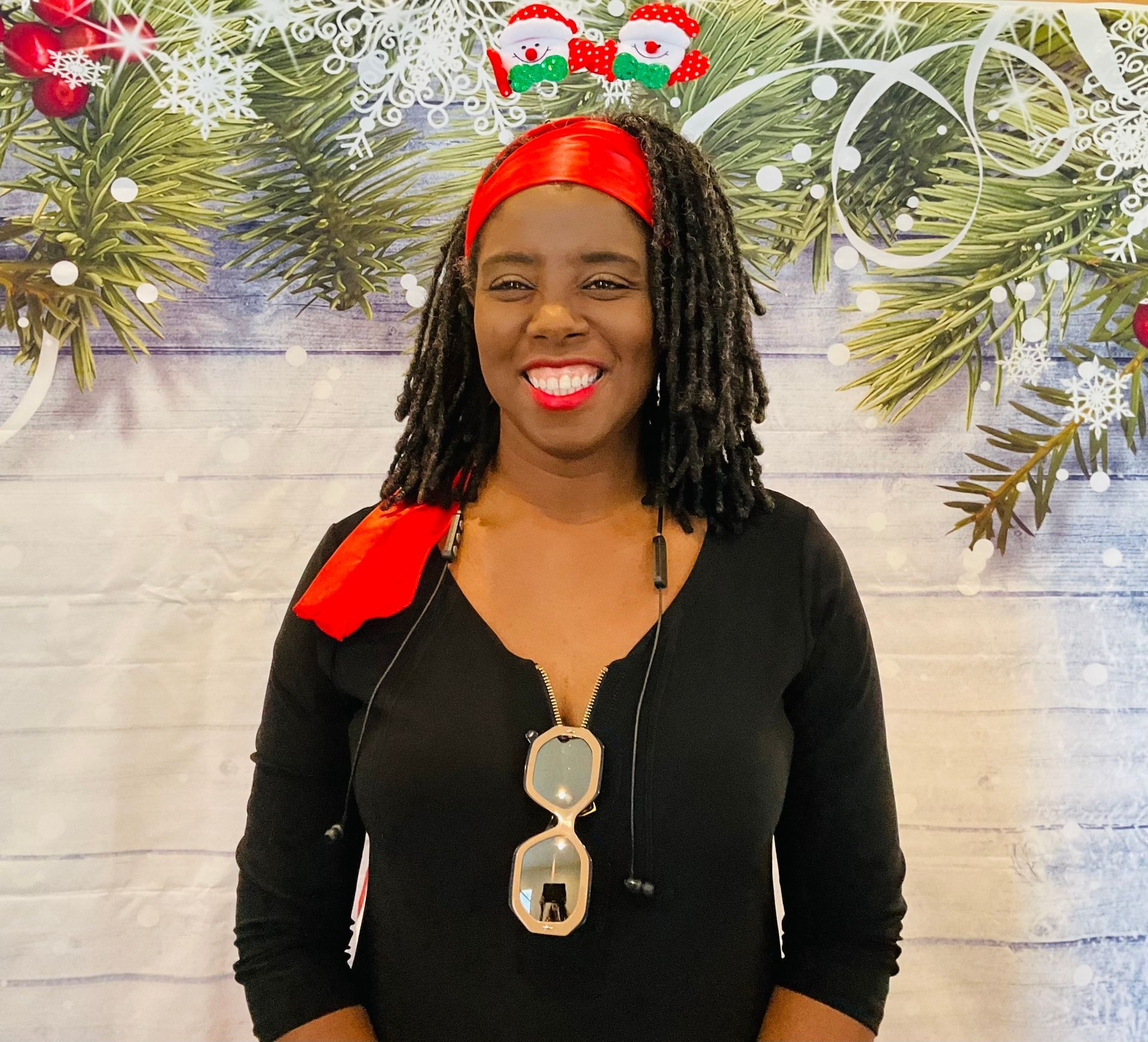A woman with dreadlocks wearing a santa headband and sunglasses