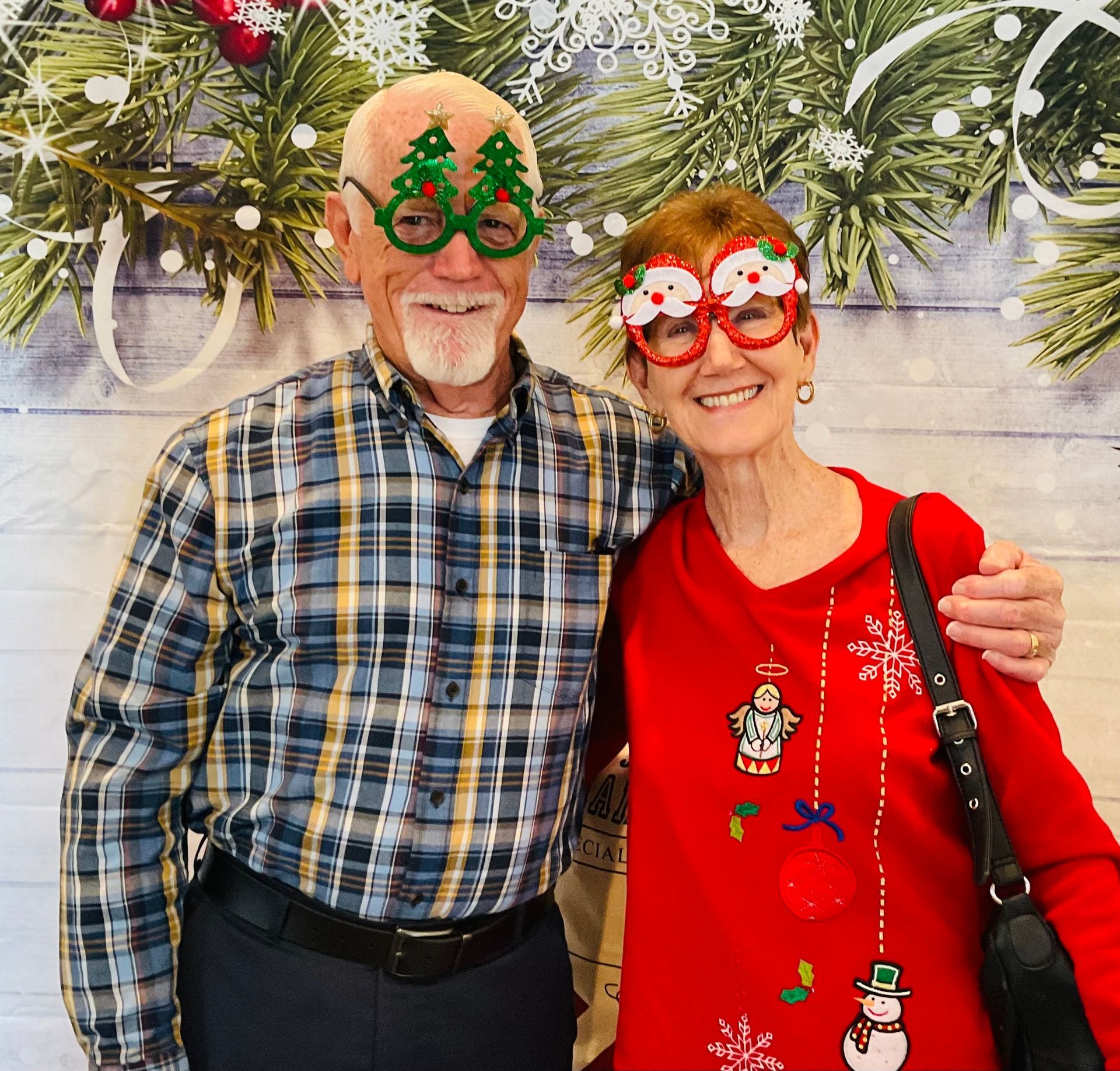 A man and woman are posing for a picture with christmas decorations in the background