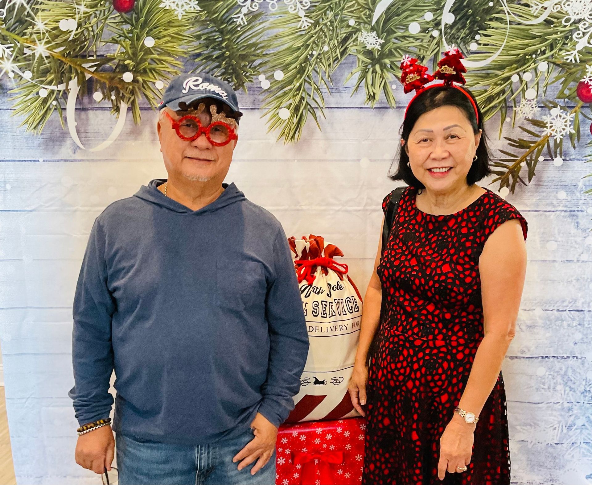 A man and a woman are posing for a picture in front of a christmas background.