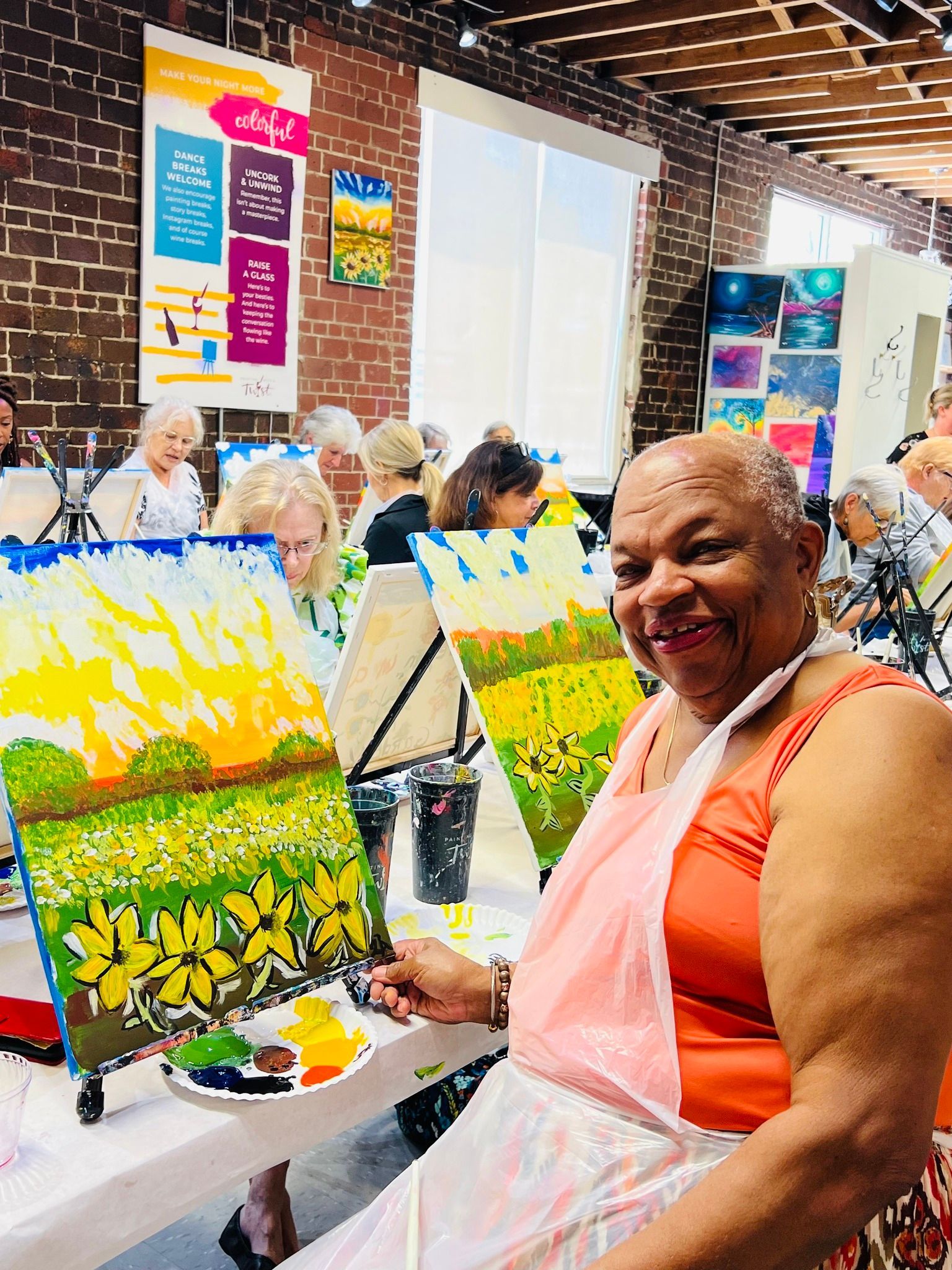 A woman is sitting at a table holding a painting.
