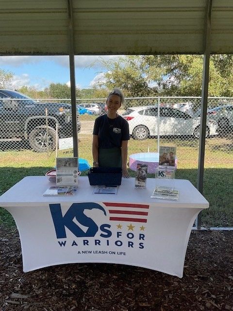 A boy is standing in front of a table that says kss for warriors