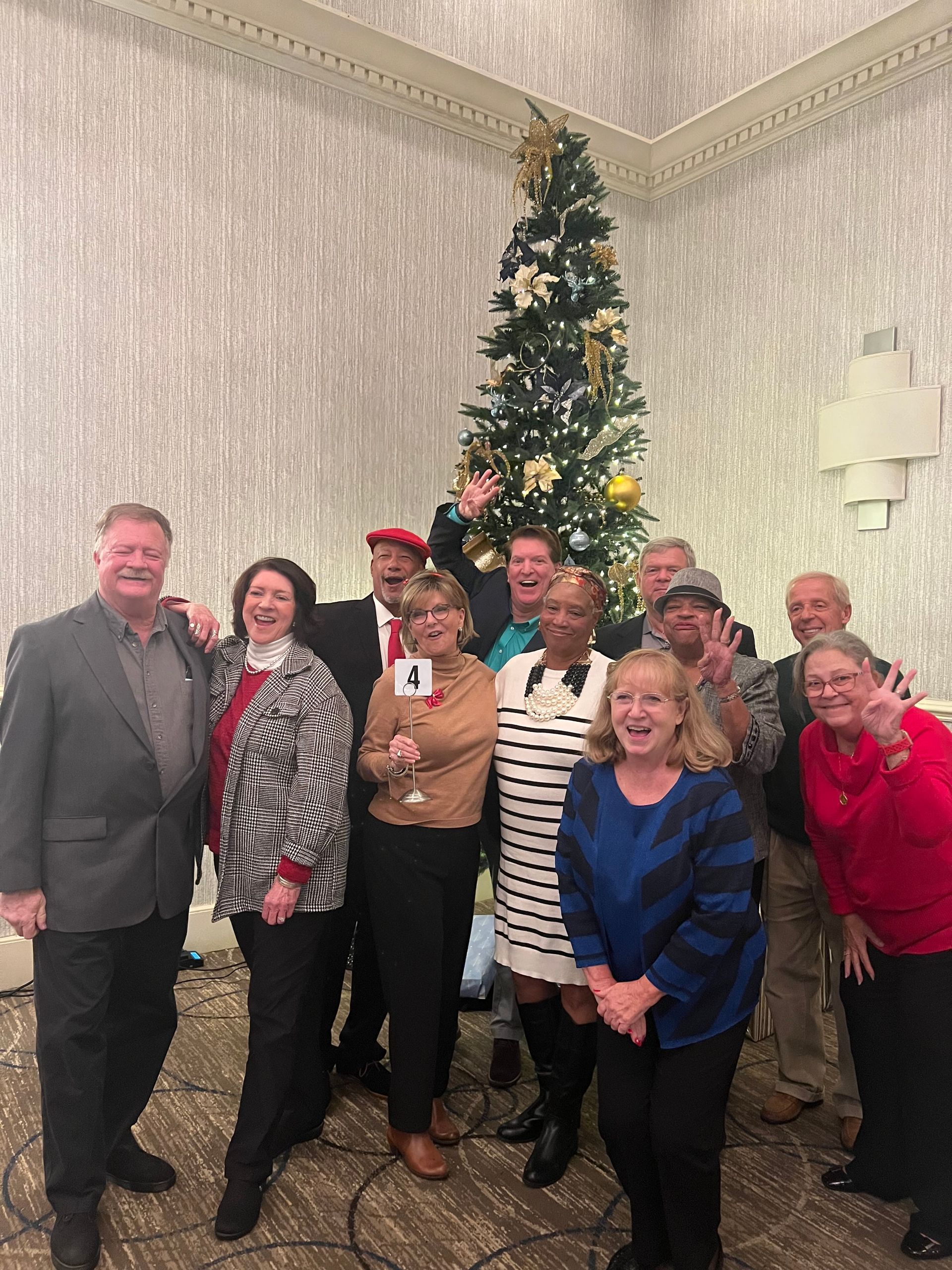 A group of people are posing for a picture in front of a christmas tree.