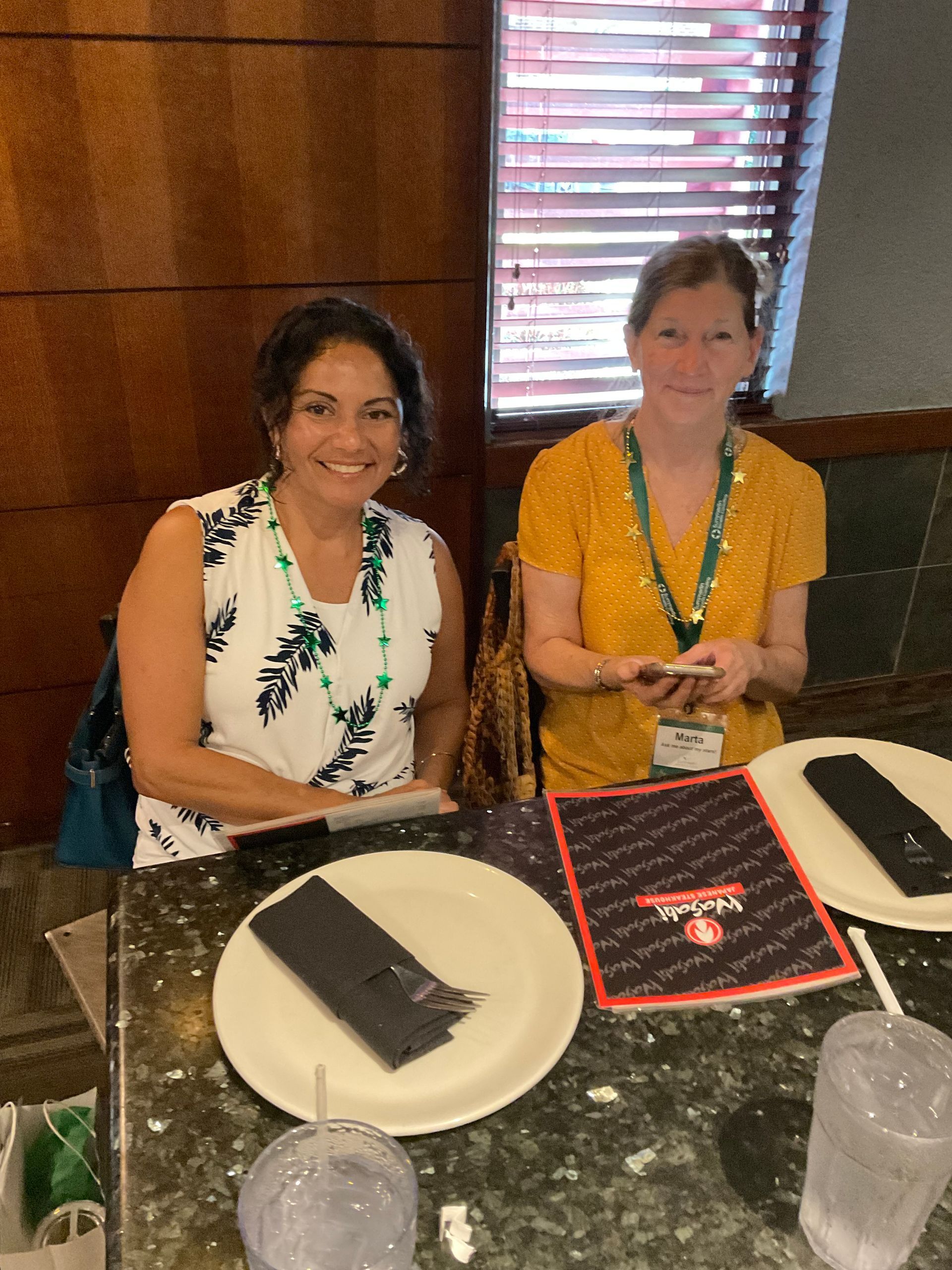 Two women are sitting at a table with plates and drinks