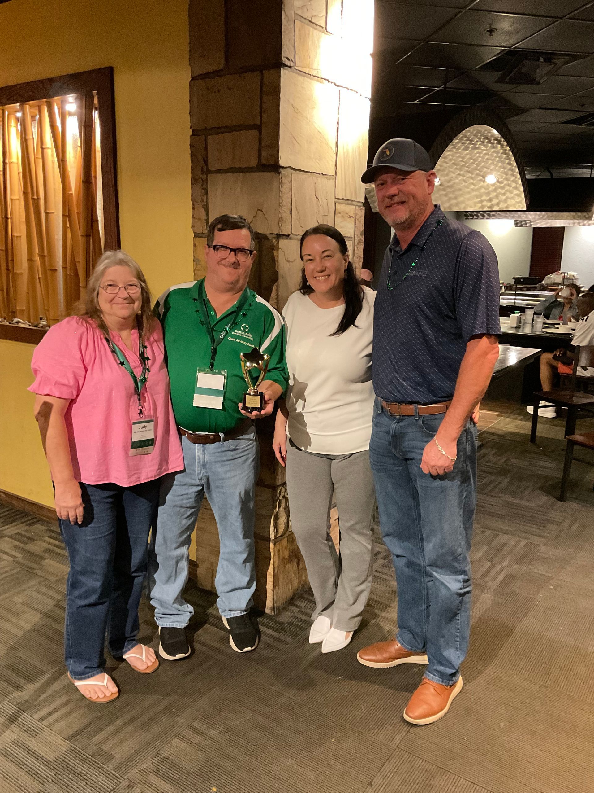 Keith, Stacy, and two Gold clients are posing for a picture in a restaurant.