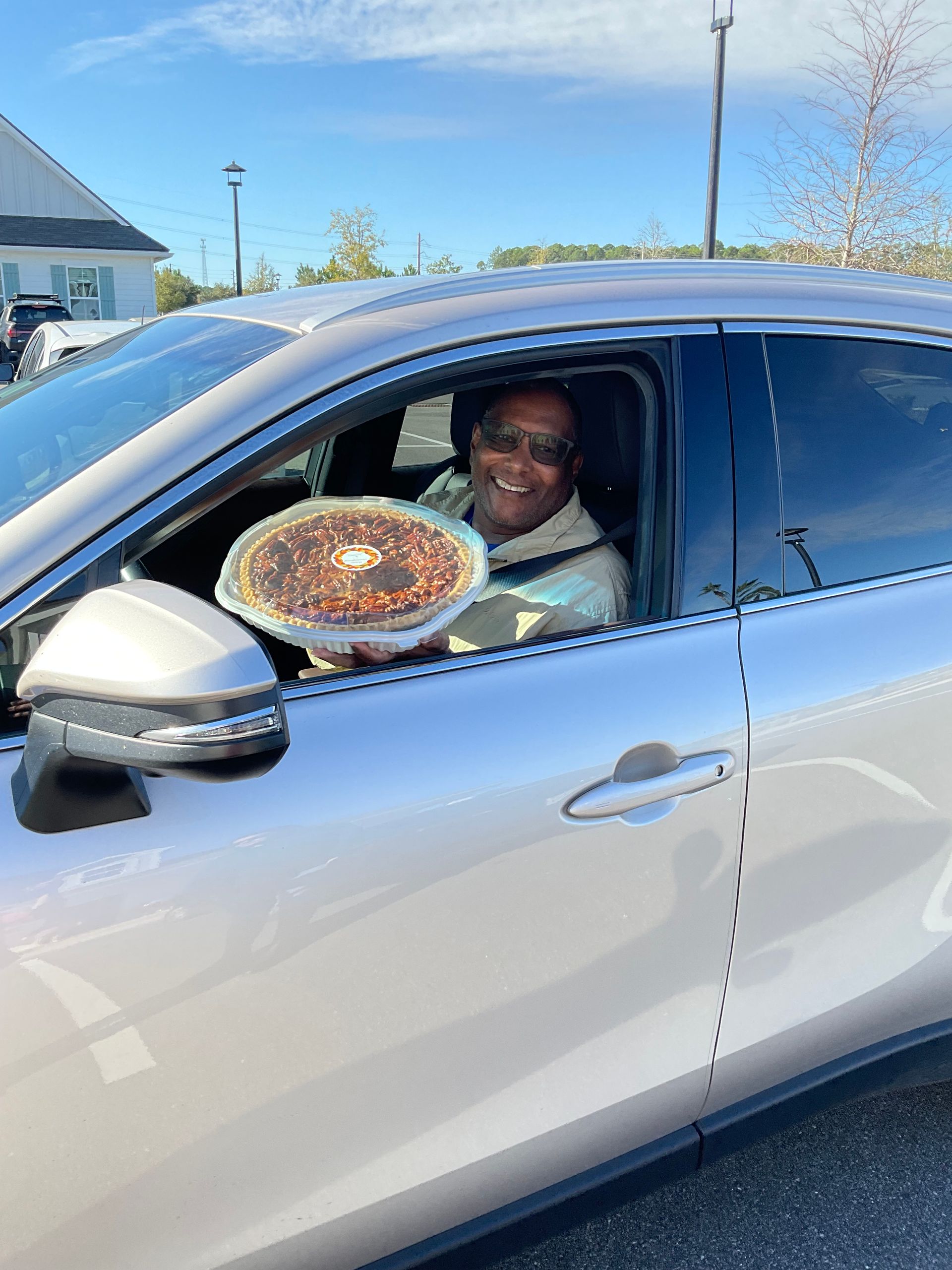 A man is sitting in a car holding a pie in his hand.