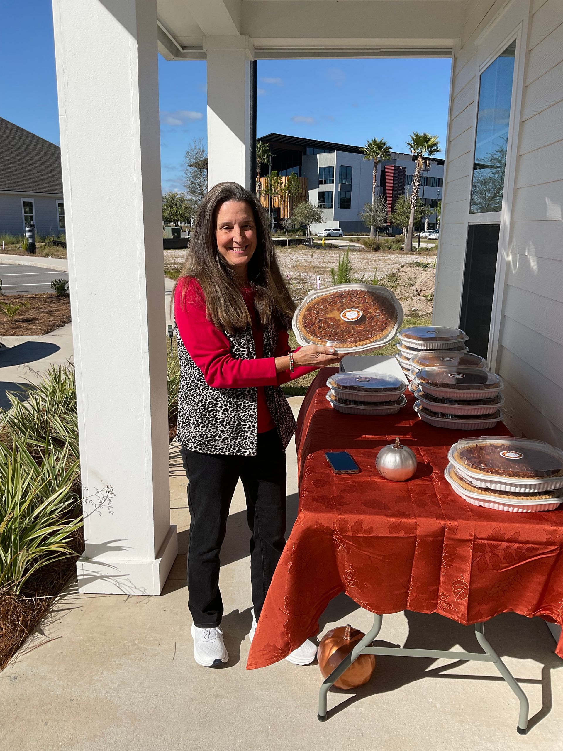A woman is standing in front of a table holding a pie.