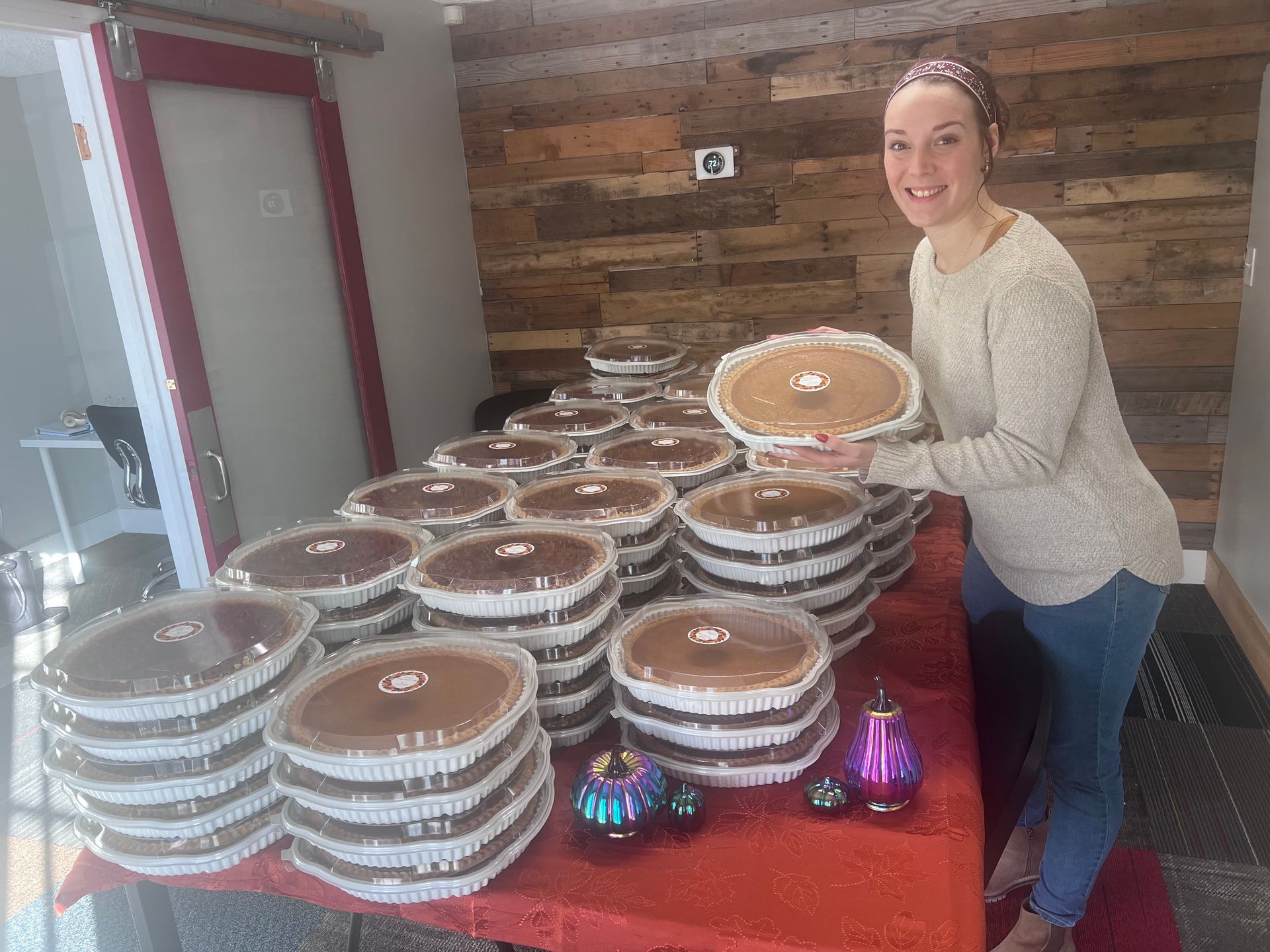 A woman is standing in front of a table full of pies.
