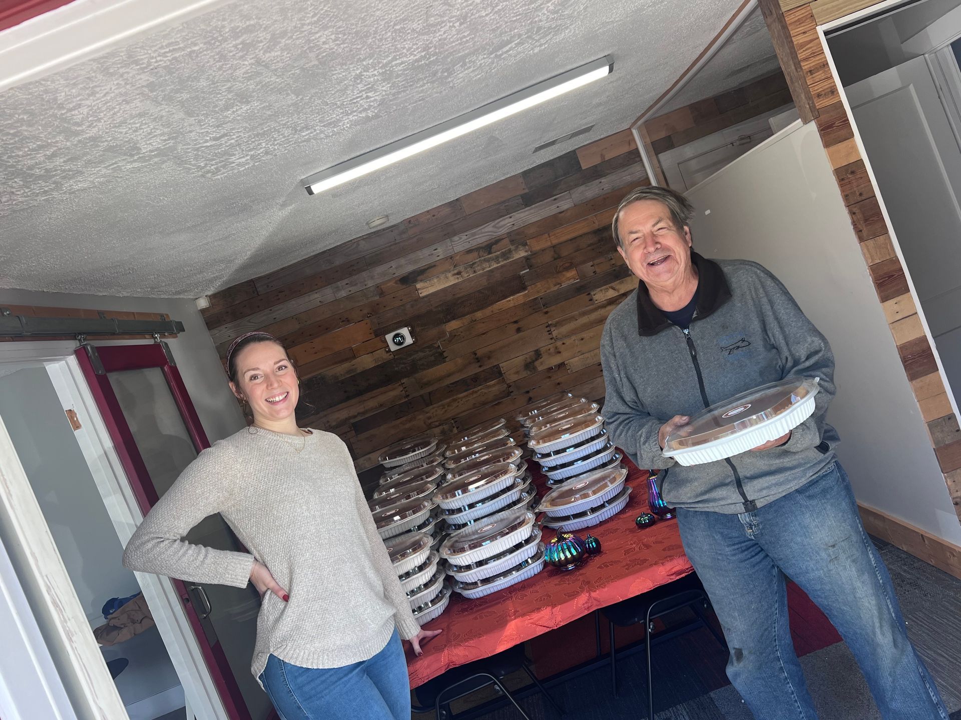 A man and a woman are standing next to each other in a room holding plates of food.