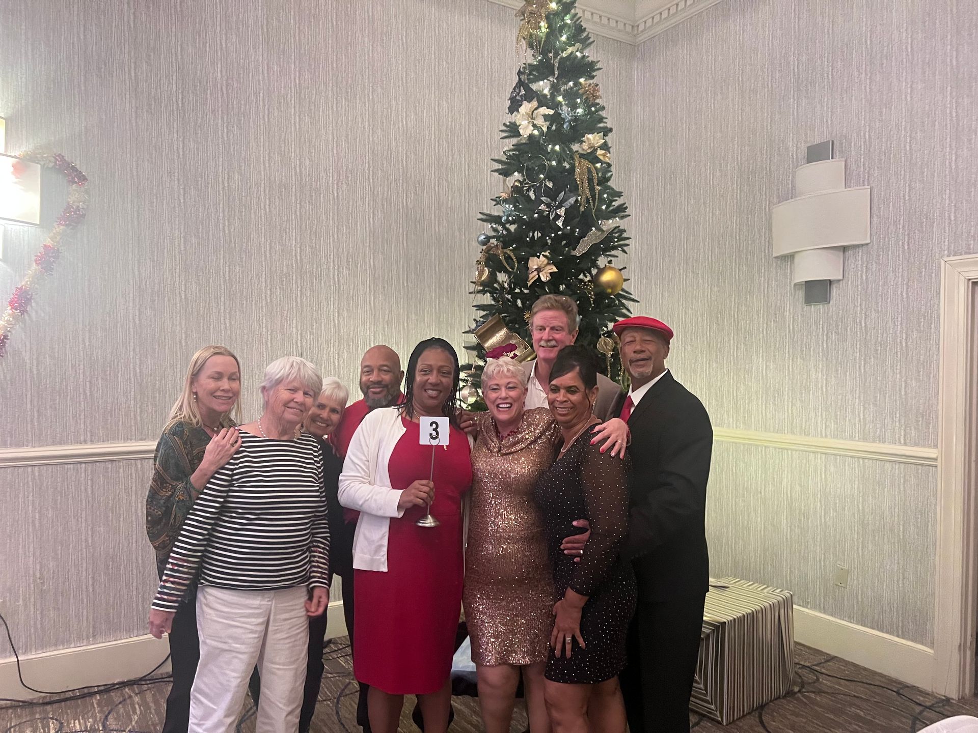 A group of people are posing for a picture in front of a christmas tree.