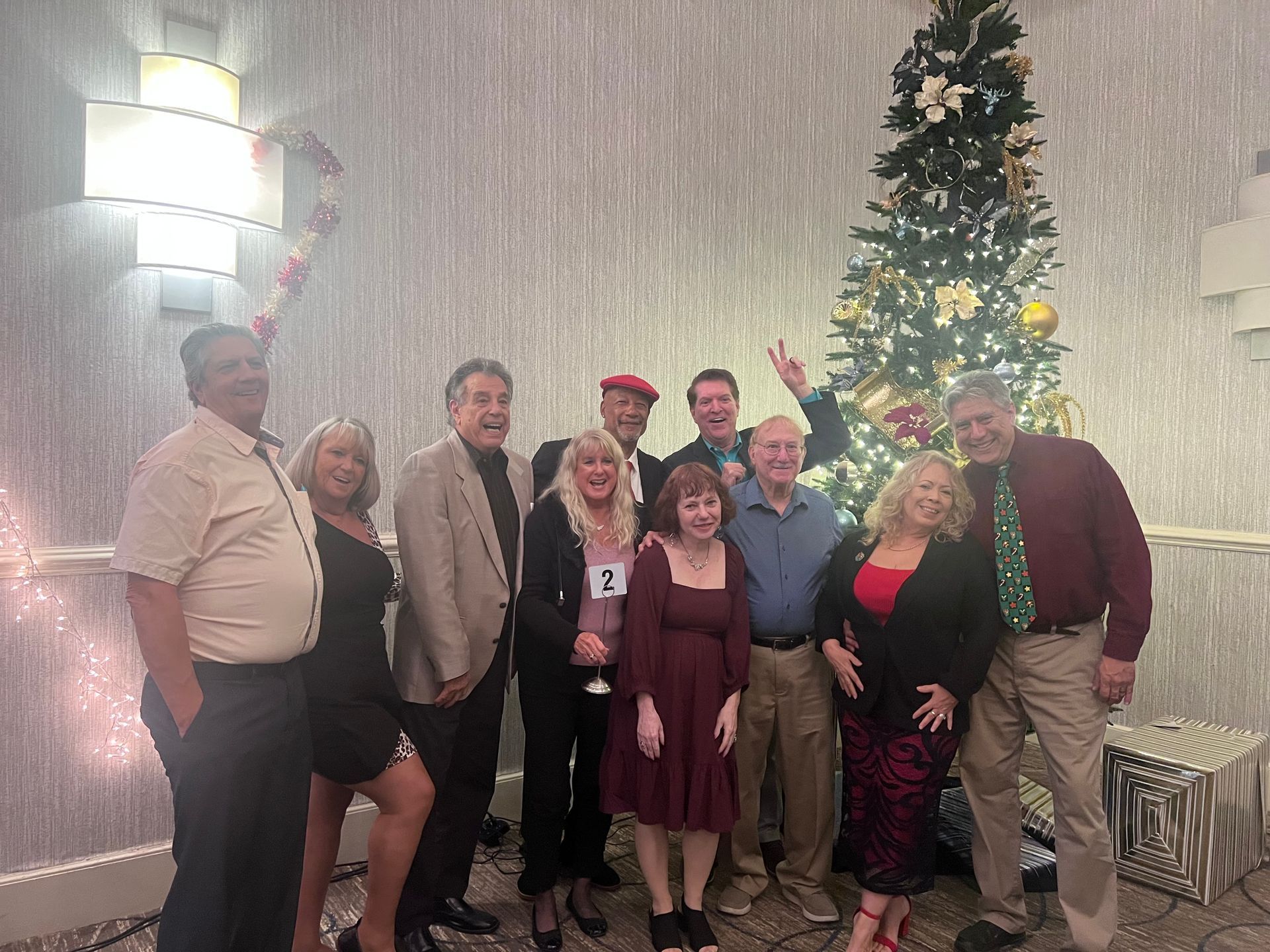 A group of people are posing for a picture in front of a christmas tree.