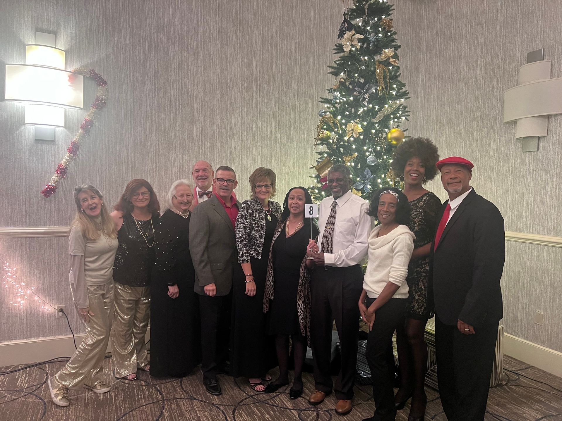 A group of people are posing for a picture in front of a christmas tree.